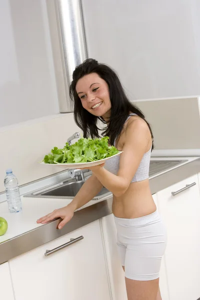 Womanholding a dish of salad in kitchen — Stock Photo, Image