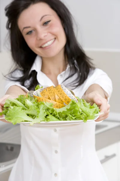 Молодая женщина представляет салатное блюдо с измерительным инструментом — стоковое фото