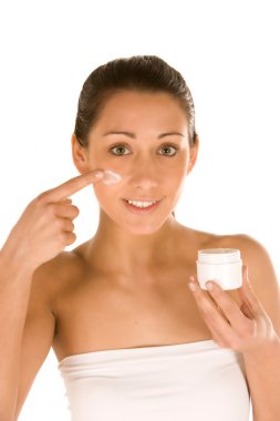 Young caucasisian brunette applying stripe of cream on her face clipart