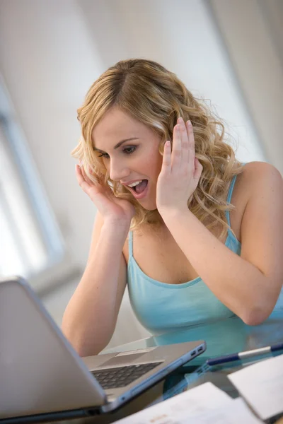 Ung kvinna med förvånade ansiktsuttryck som arbetar på laptop — Stockfoto