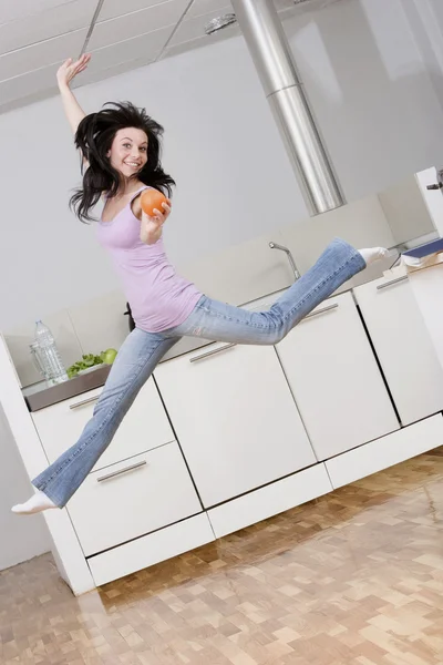 Woman jumping in kitchen — Stock Photo, Image