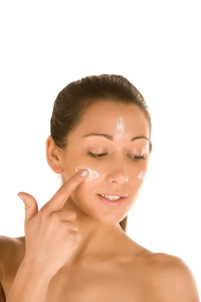 Joven morena caucásica aplicando una raya de crema en su cara — Foto de Stock