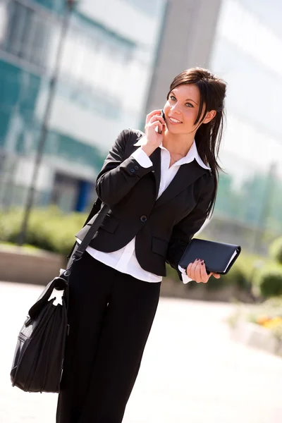 Молодая улыбающаяся деловая женщина на улице делает звонок по мобильному телефону — стоковое фото