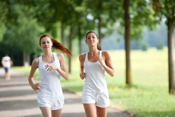 Two young woman running in a park — Stock Photo, Image