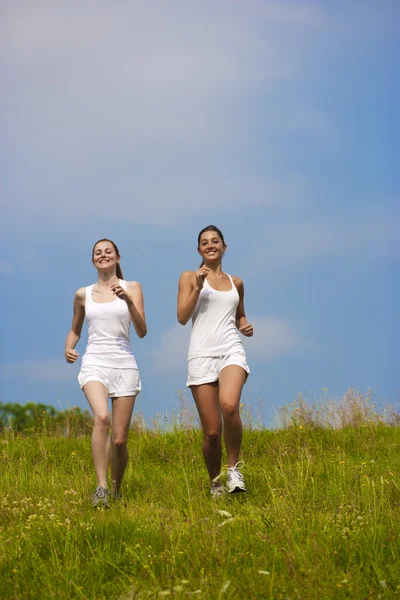 Two young woman running in a park — Stock Photo, Image