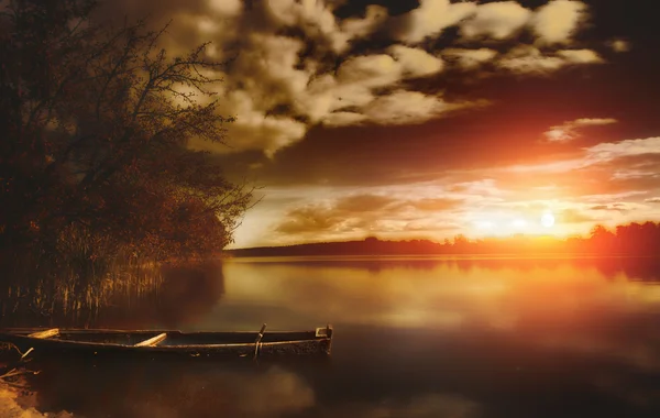 在充满活力的夏天日落期间平静湖面上钓鱼船 图库图片