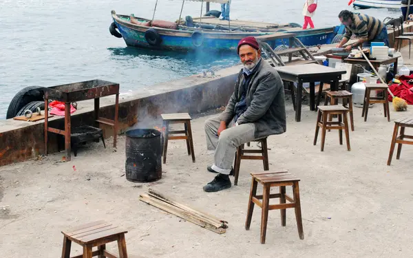 İstanbul. ihtiyar bir adamın kendini ateşin ısıtıyor