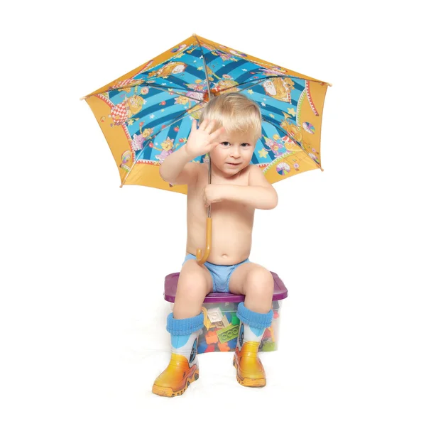 The boy under an umbrella sits on a box — Stock Photo, Image