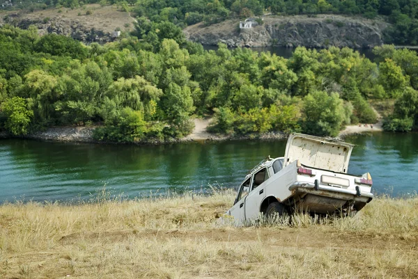 stock image Abandoned car on the riverbank near the water