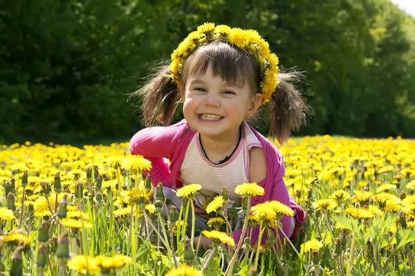 Smiling girl sitting on the dandelion field — Stock Photo, Image