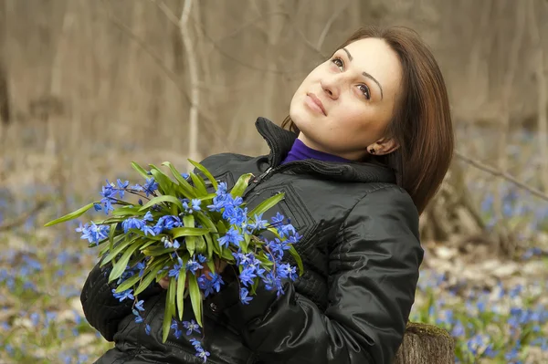 Una chica joven con un montón de campanas azules en el bosque de primavera —  Fotos de Stock