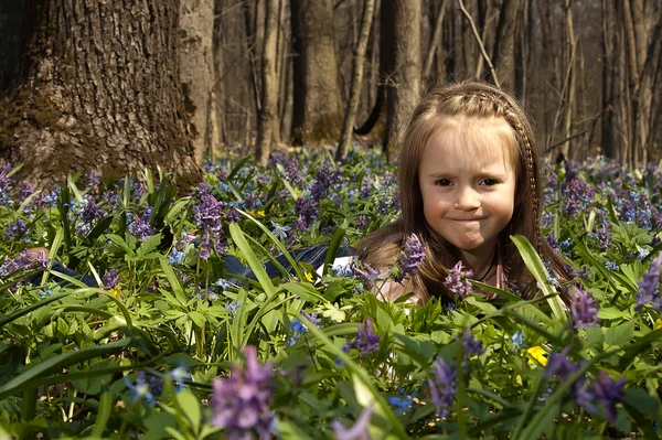 A Girl among colorful flowers in spring forest — Stock Photo, Image