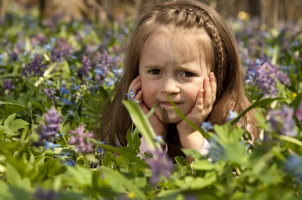 En flicka bland färgglada blommor i vår skog — Stockfoto