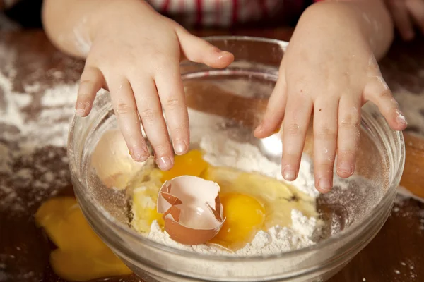 Dítěte ruku na mísy s moukou a rozbité vajíčko — Stock fotografie