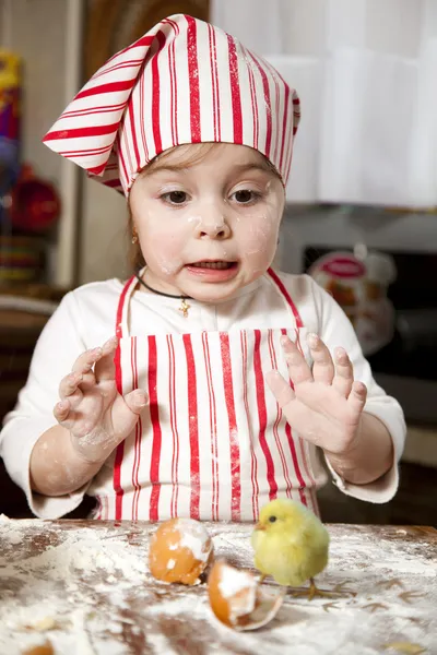 Pequeño chef en la cocina, con delantal y pañuelo en la cabeza, surpr — Foto de Stock
