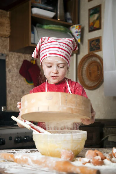 Pequeño chef en la cocina con delantal y pañuelo en la cabeza — Foto de Stock