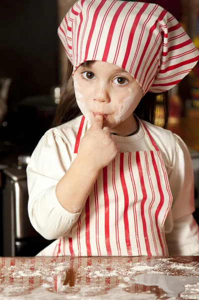 Malý kuchař v kuchyni nosí zástěru a šátek — Stock fotografie