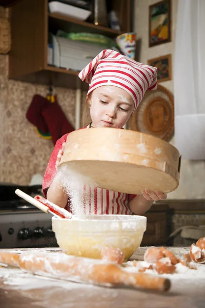Pequeño chef en la cocina con delantal y pañuelo en la cabeza — Foto de Stock