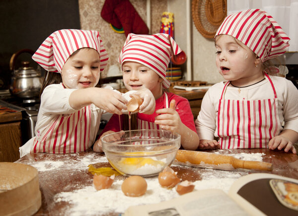 Three little chefs enjoying in the kitchen making big mess. Litt