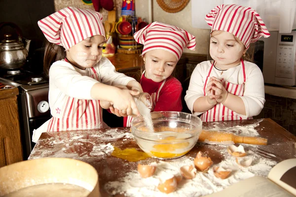 Három kis szakácsok élvezi a nagy rendetlenség konyhában. Litt Stock Fotó