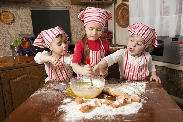 Három kis szakácsok élvezi a nagy rendetlenség konyhában. Litt Stock Fotó