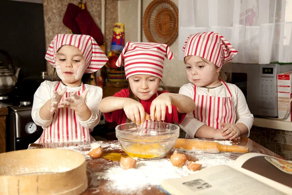 Három kis szakácsok élvezi a nagy rendetlenség konyhában. Litt Stock Kép