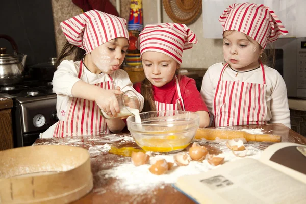Három kis szakácsok élvezi a nagy rendetlenség konyhában. Litt Stock Kép