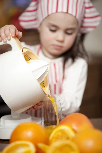 Lilla flickan att göra friska apelsinjuice — Stockfoto