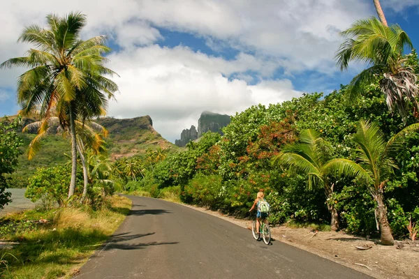 Girl riding a bicycle through the tropical island Bora Bora , French Polynesia — Stock Photo, Image