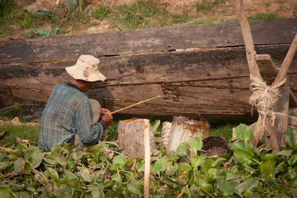 Mies korjaamassa venettä, Kambodza — kuvapankkivalokuva