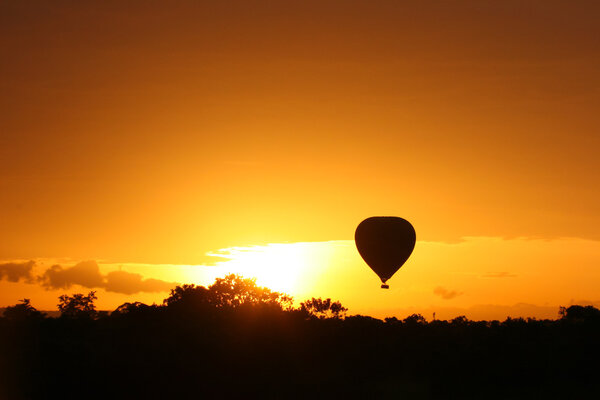 Hot air balloon flying at sunrise over Masai Mara Park, Kenya