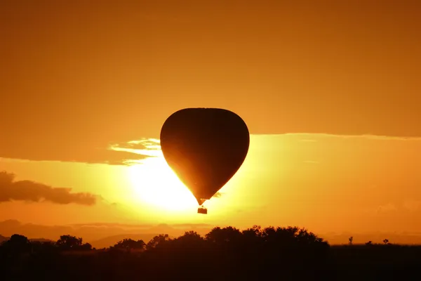 Heißluftballon fliegt bei Sonnenaufgang über dem Masai Mara Park, Kenia — Stockfoto