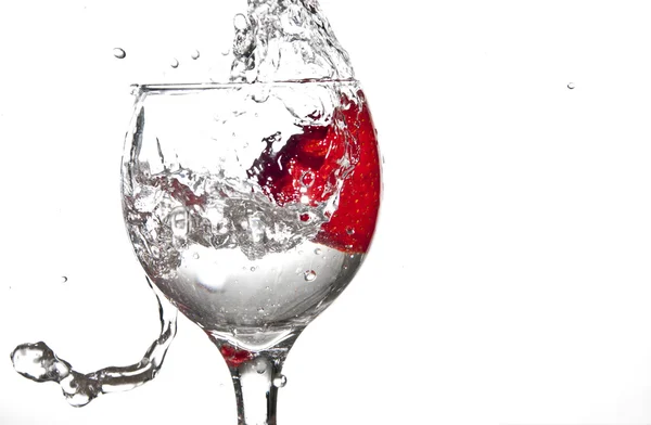 Erdbeere spritzt in ein Weinglas lizenzfreie Stockbilder
