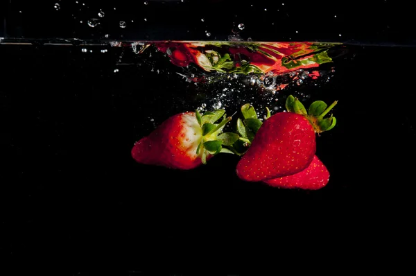 Fraises éclaboussant dans l'eau Photo De Stock