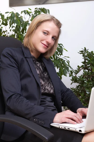 Donna d'affari seduta e che lavora con notebook in ginocchio — Foto Stock