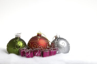 Üç Noel baubles ve kar bazı küçük hediye paketleri