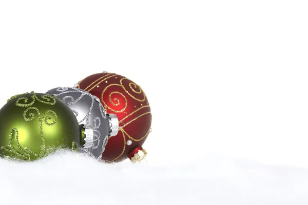 Три різдвяні кульки на снігу на білому тлі — стокове фото