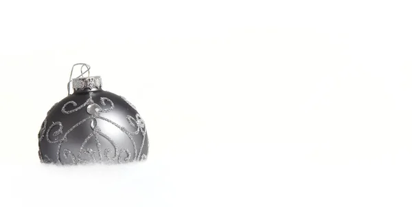 En silver julgran boll i snön som en närbild — Stockfoto