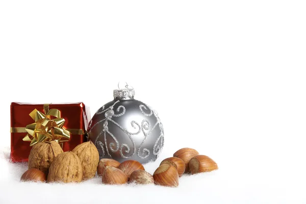 Boule d'arbre de Noël, cadeaux et noix dans la neige — Photo