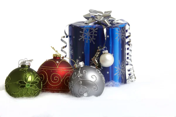Una palla di Natale rossa, verde e argento e un regalo sulla neve — Foto Stock