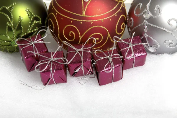 Tre julgranskulor och några små presentförpackningar på vit bakgrund — Stockfoto
