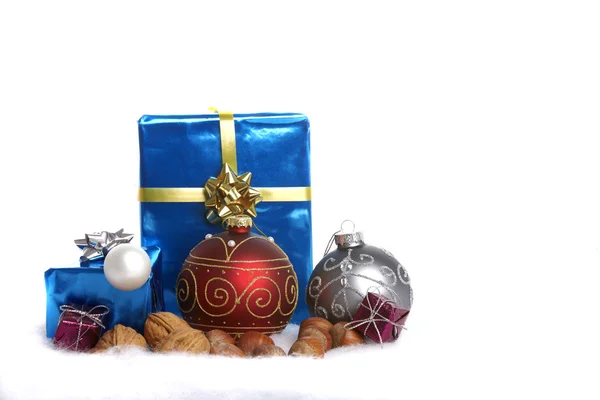 Рождественские шары, орехи и подарки в снегу — стоковое фото