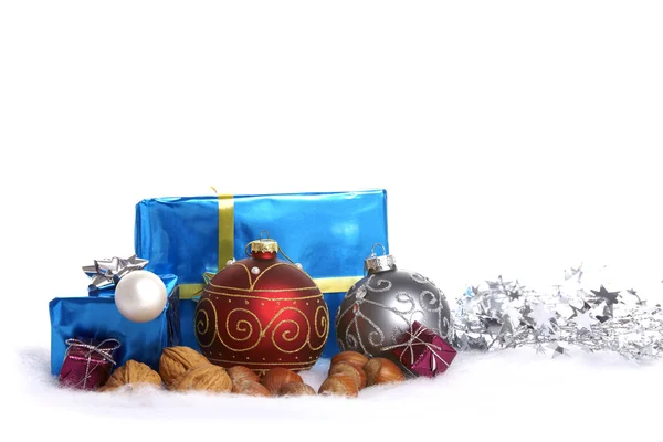 Christmas tree balls, nuts and gifts in the snow — Stock Photo, Image