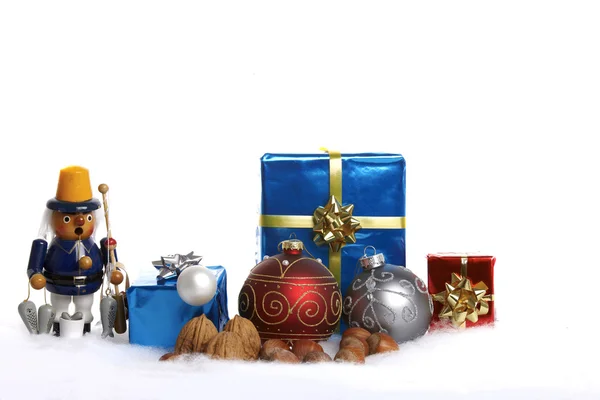 Christbaumkugeln, Holzfigur, Geschenke und Nüsse im Schnee — Stockfoto