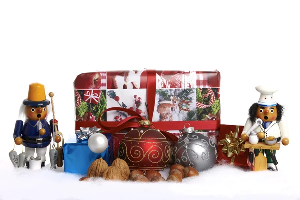 Christbaumkugeln, Holzfigur, Geschenke und Nüsse im Schnee — Stockfoto
