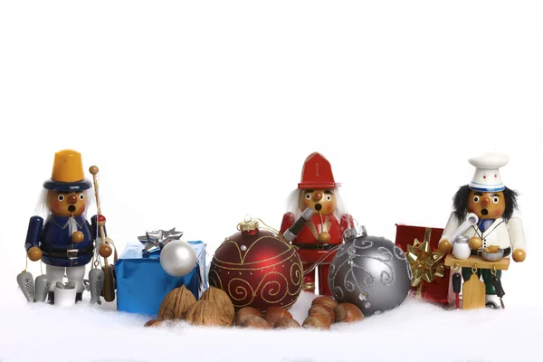 Christmas tree balls, wooden figure, gifts and nuts in the snow — Stock Photo, Image