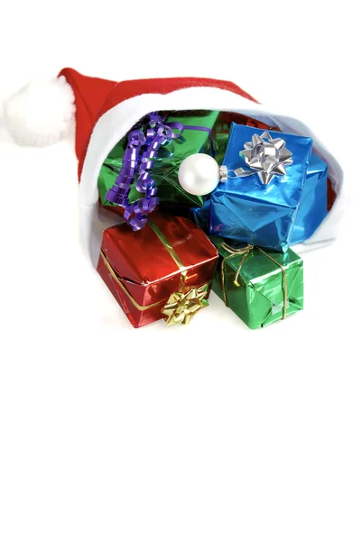 Many colorful christmas gifts in a santa claus cap on white background — Stock Photo, Image