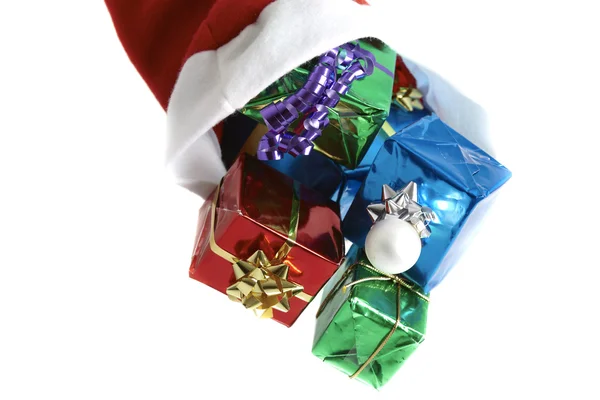 Noel Baba şapkası beyaz zemin üzerine yapılan pek çok renkli Noel hediyeleri — Stok fotoğraf
