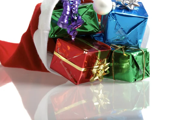 Muitos presentes de Natal coloridos em um boné de Papai Noel no fundo branco — Fotografia de Stock
