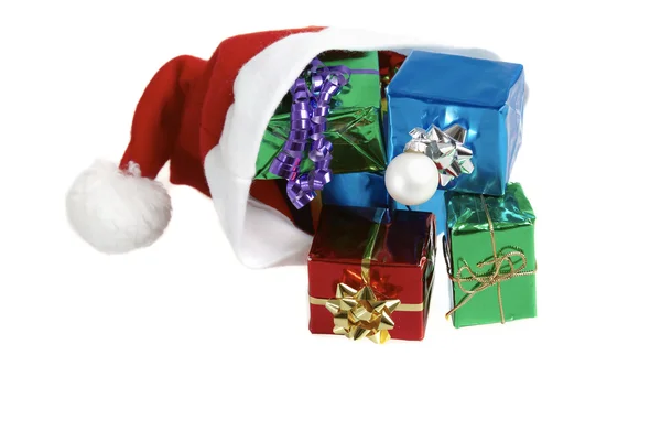 Many colorful christmas gifts in a santa claus cap on white background — Stock Photo, Image